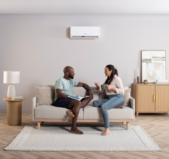 two homeowners sat on sofa enjoying air conditioning