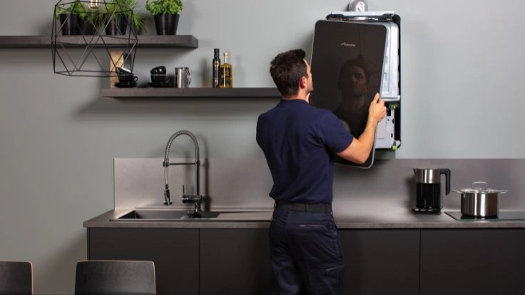 Installer in front of Greenstar 8000 style boiler putting casing back on