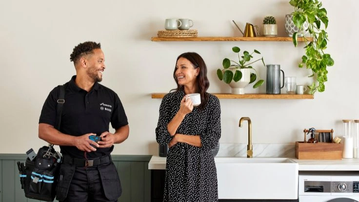 Installer and women talking in kitchen smiling