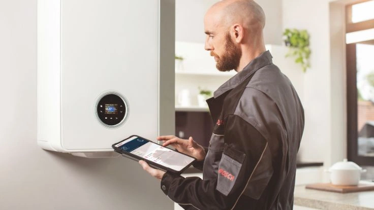 Installer on his tablet in front of a boiler