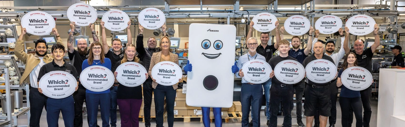 Worcester Bosch employees holding Which? signs with Bobby the Boiler in the factory